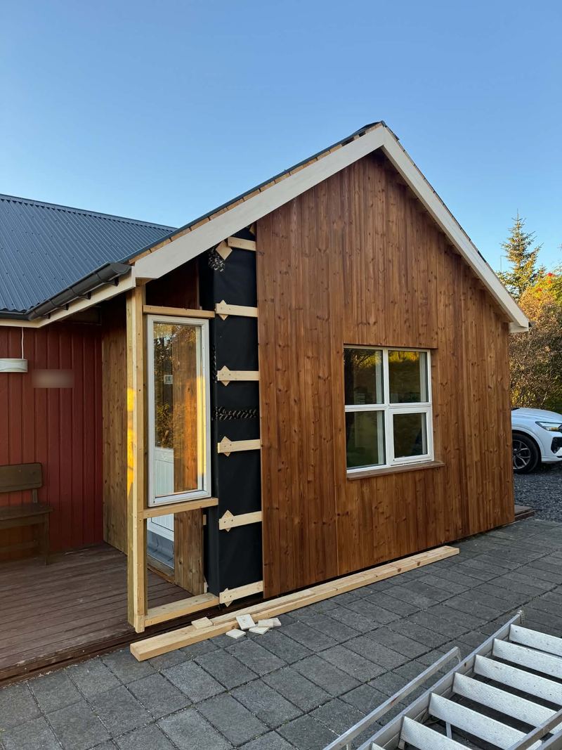 Viðbyggingin klædd með standandi viðarklæðningu og nýjum gluggum